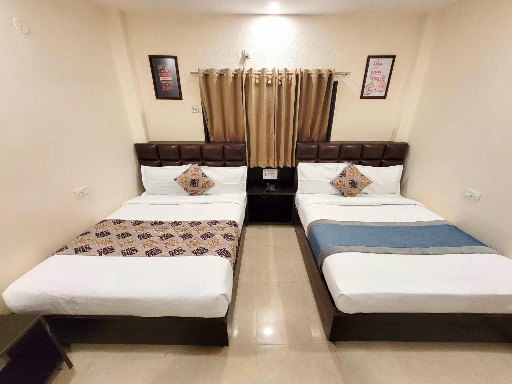 2 Betten in einem kleinen Zimmer mit Vorhängen in der Unterkunft The Nirvana By Urban Galaxy in Amritsar