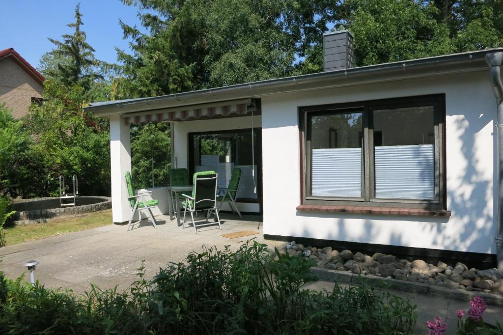 ein kleines weißes Haus mit einer Terrasse mit Stühlen in der Unterkunft Sonne in Elmenhorst