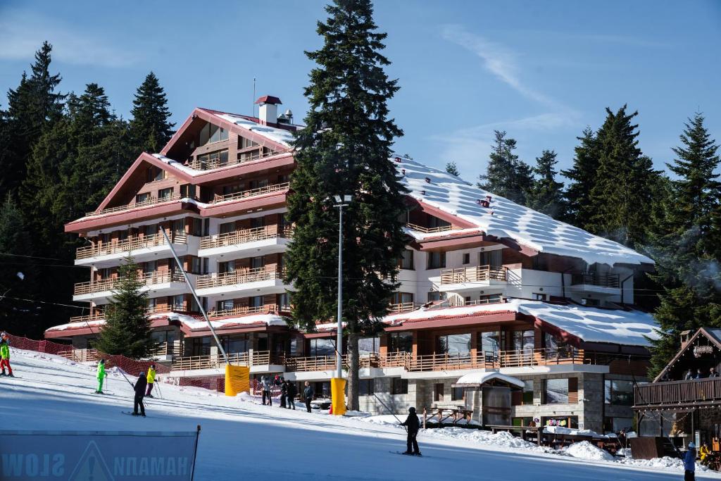 un gran edificio con esquiadores delante de él en la nieve en Musala Hotel, en Borovets