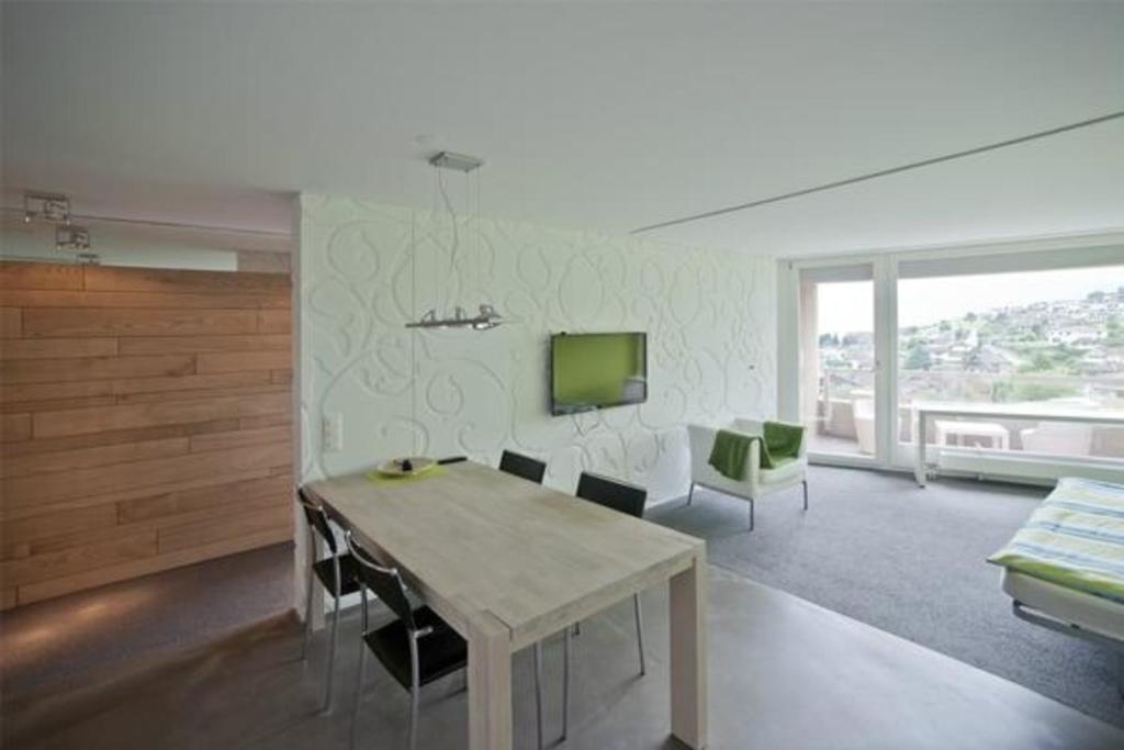 uma sala de estar com uma mesa e cadeiras e uma televisão em Hoegerli Alpenblick em Weggis