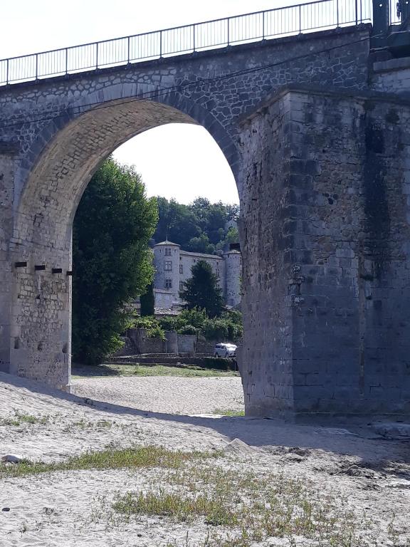 an old stone bridge with an arch over a field at Gîte Amour D&#39;ardèche in Saint-Sernin
