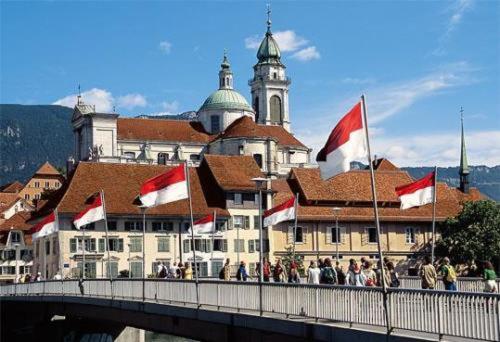 a bridge with red and white flags in front of a building at Hotel Ambassador in Solothurn