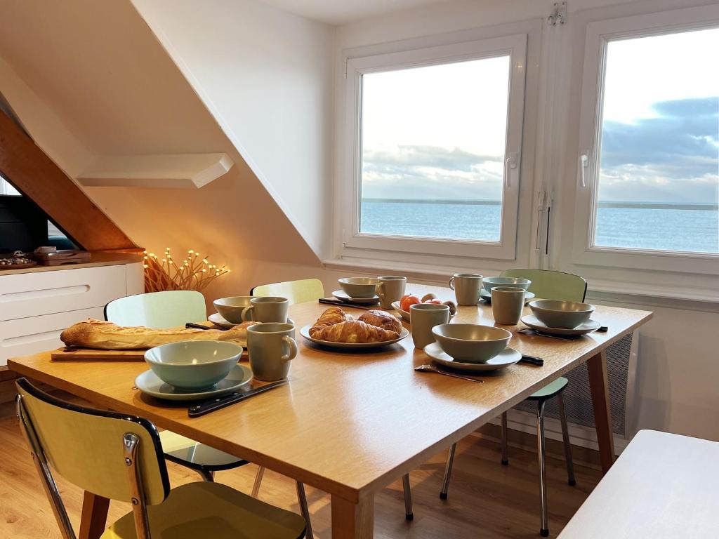 uma mesa de jantar com comida e duas janelas em Fenêtres sur mer em Cayeux-sur-Mer