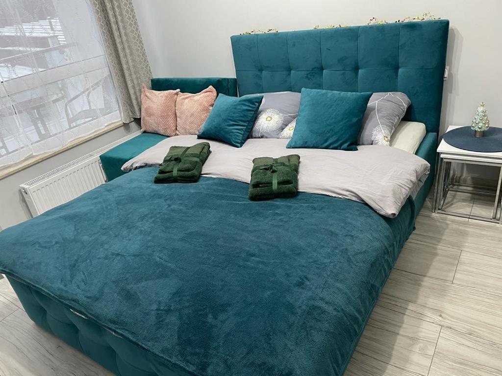 a large blue bed with pillows on top of it at APARTAMENT USTROŃ 84 in Ustroń