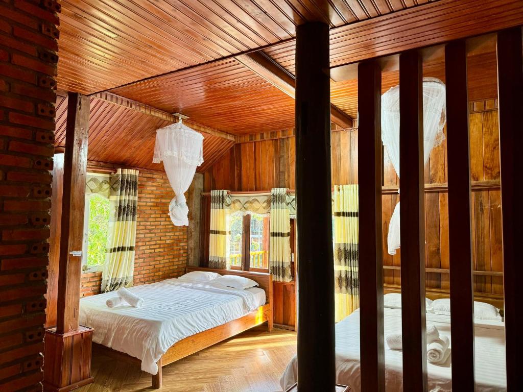 1 dormitorio con 1 cama en una habitación con techos de madera en Lava Rock Viet Nam Lodge, en Cát Tiên
