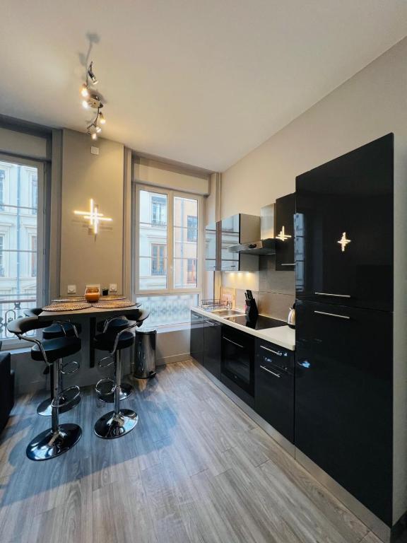 Il comprend une cuisine équipée d'une table et d'un réfrigérateur noir. dans l'établissement Cosy Masséna Apartment - Parc Tête d'Or, à Lyon