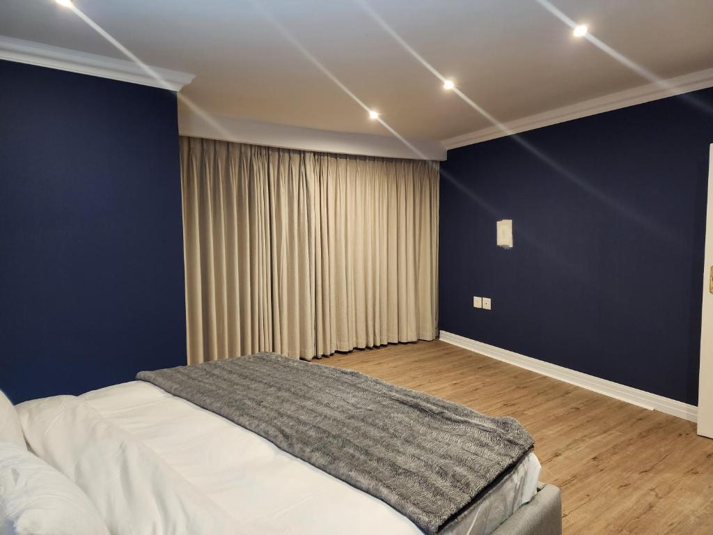 a bedroom with a bed and a blue wall at Bryanston Crescent in Johannesburg