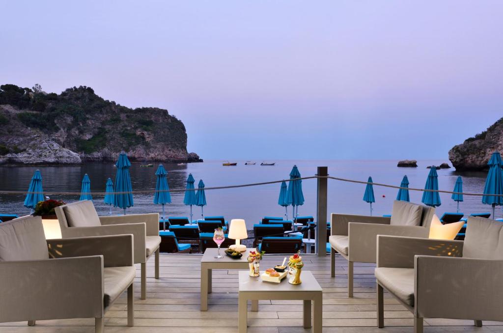 un resort con sedie, tavoli e ombrelloni di La Plage Resort a Taormina