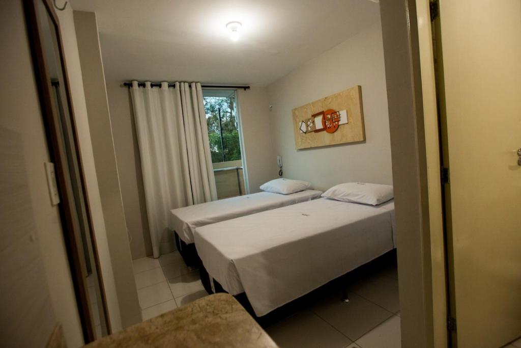 two beds in a room with a window at Várzea HOTEL in Sobral