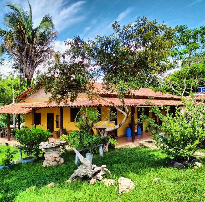 una casa amarilla con árboles delante de ella en Pousada Paineira, en São Gonçalo do Rio das Pedras
