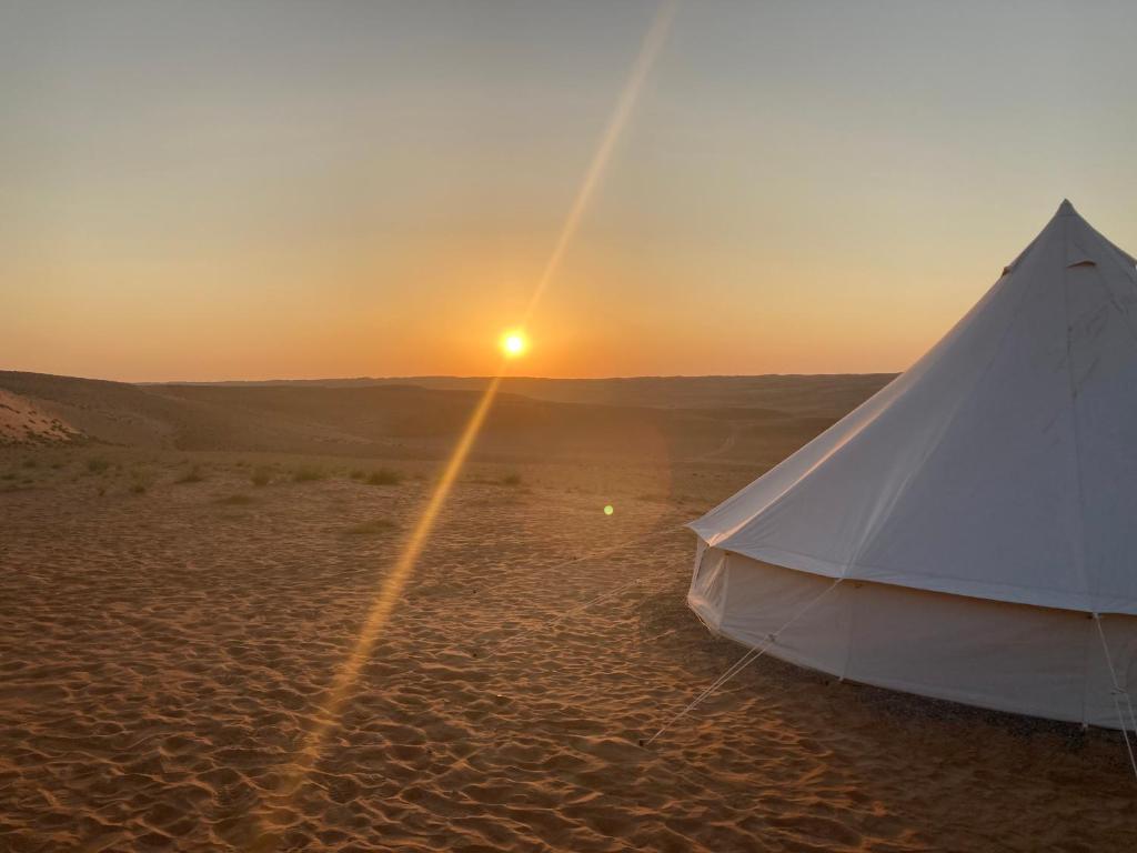 une tente blanche dans le désert au coucher du soleil dans l'établissement Desert Moments Glamping - full privacy, à Muntarib