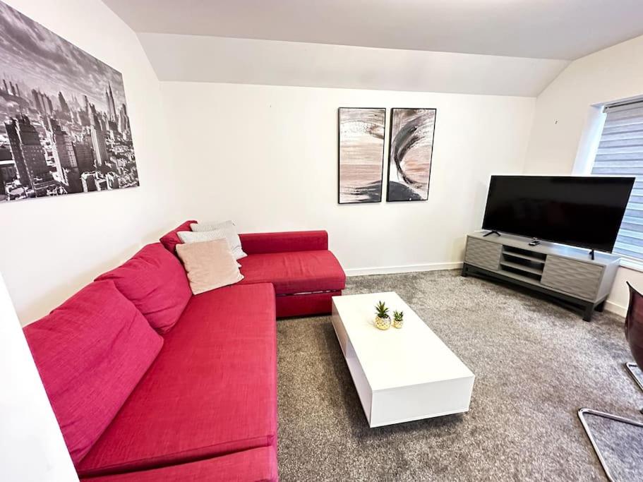 Paradigm House, Delightful 2-Bedroom Flat 4, Oxford في أوكسفورد: غرفة معيشة مع أريكة حمراء وتلفزيون بشاشة مسطحة
