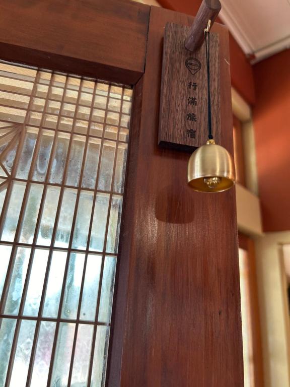 eine Holztür mit einem Schild neben einem Fenster in der Unterkunft 行滿旅宿&包棟烤肉親子寵物大庭院 in Zhuqi