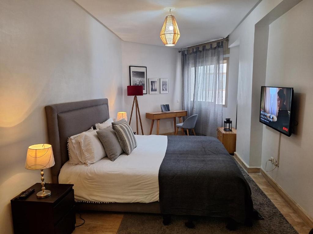 a bedroom with a large bed and a tv at Grand appartement de luxe vue mer in Casablanca