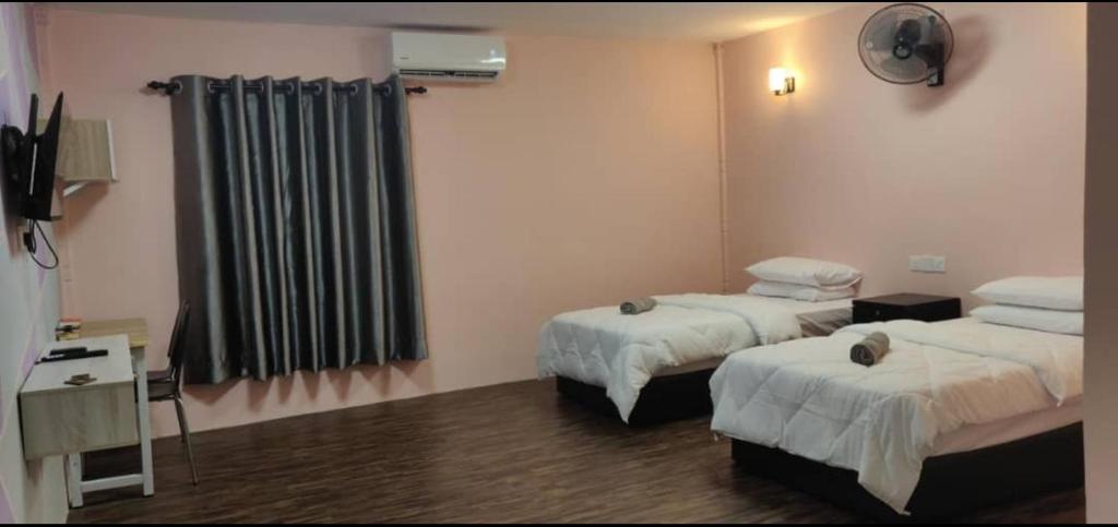 a hotel room with two beds and a television at Tazrah roomstay (1 queen or 2 twin super single room) in Kuala Rompin