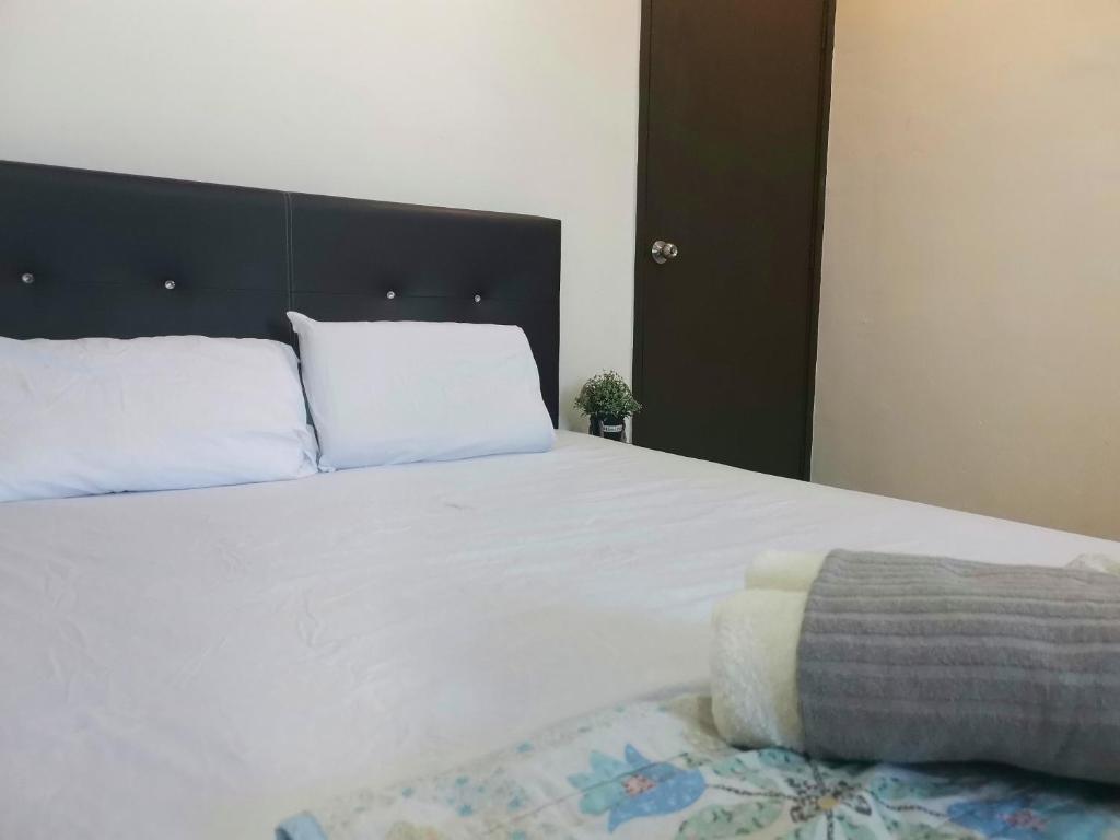 a bedroom with a large white bed with a black headboard at White House 19 Room B in Bukit Mertajam