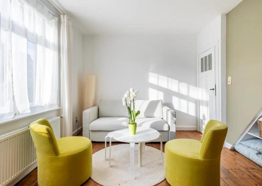 un soggiorno con 2 sedie gialle e un tavolo di Vitaflow logies a Koksijde