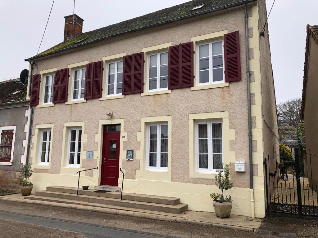 une maison avec une porte rouge dans une rue dans l'établissement Le Voyageur, à Saint-Bonnet-Tronçais
