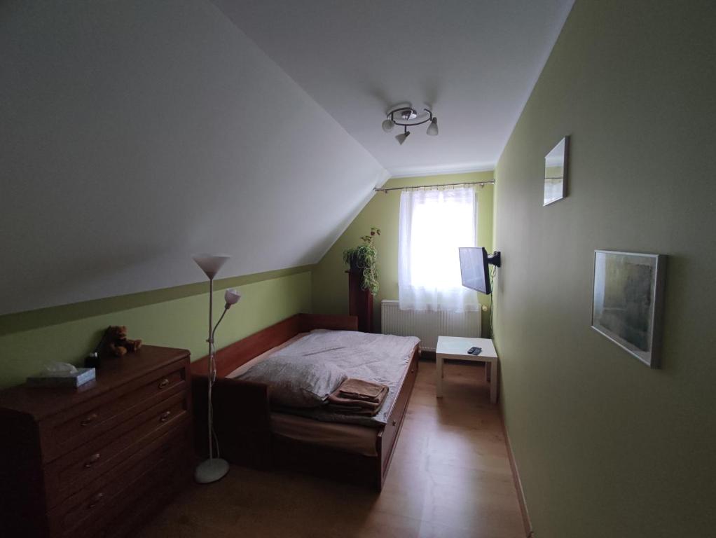 a bedroom with a bed and a dresser and a window at Zielony Zakątek in Piechowice