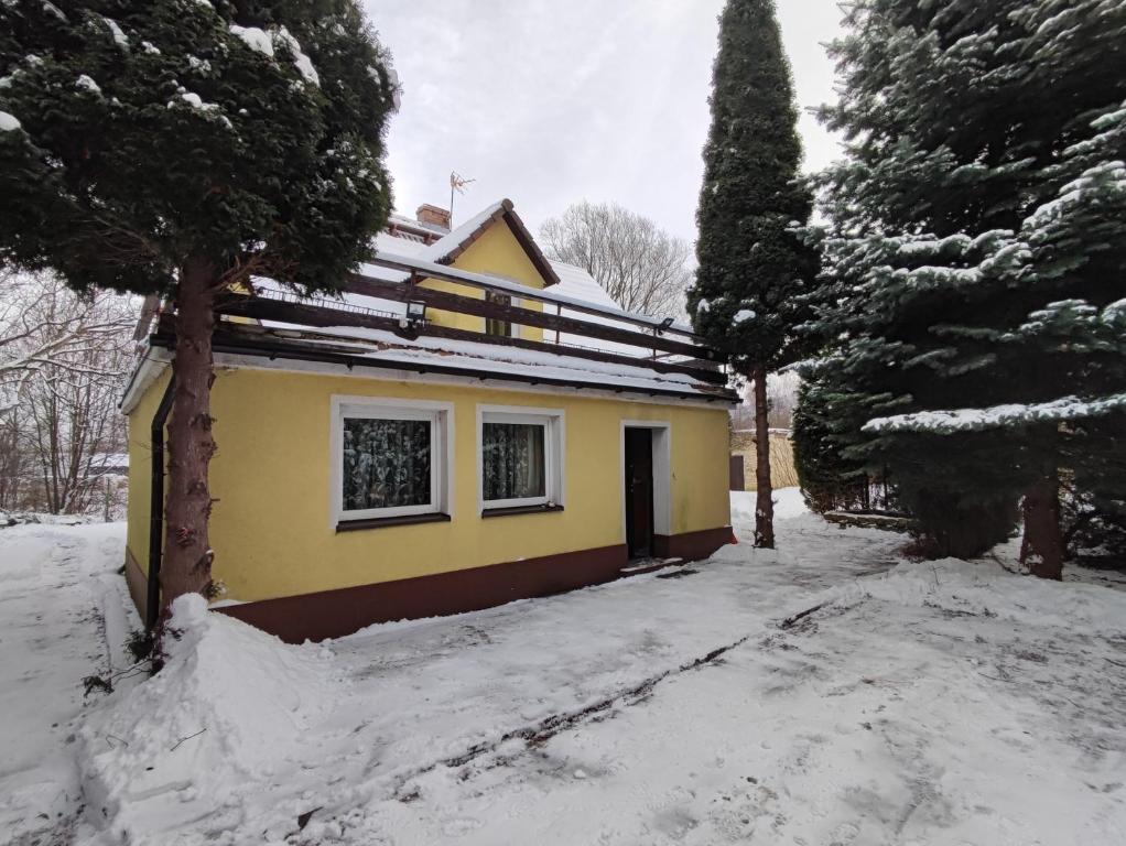 a yellow house with snow on the ground at Zielony Zakątek in Piechowice
