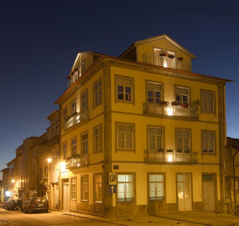 a large yellow building with windows and balconies at night at Domus 26 Guesthouse - B&B in Braga