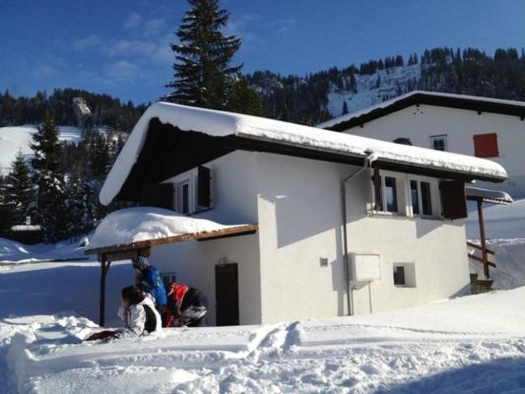 two people sitting in the snow in front of a building at Bambi in Wirzweli