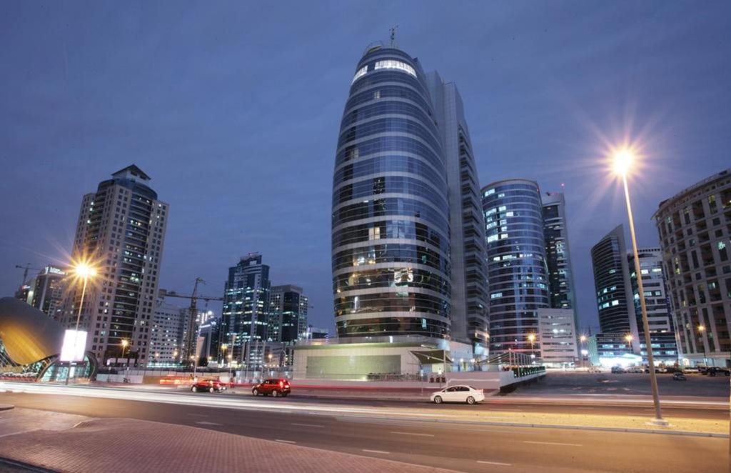 a city skyline with tall buildings at night at Citadines Metro Central Hotel Apartments in Dubai