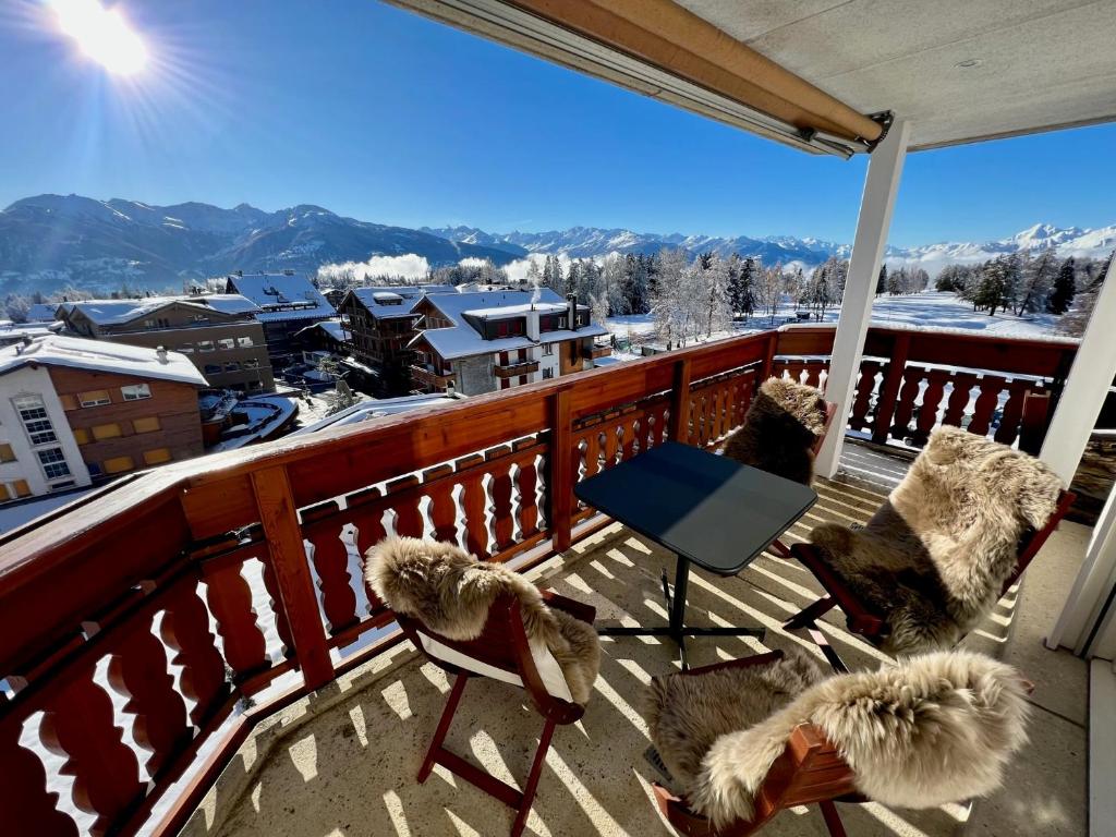 einen Balkon mit Stühlen und Blick auf einen verschneiten Berg in der Unterkunft Exclusive Comfy Apartment in Central Crans-Montana in Lens