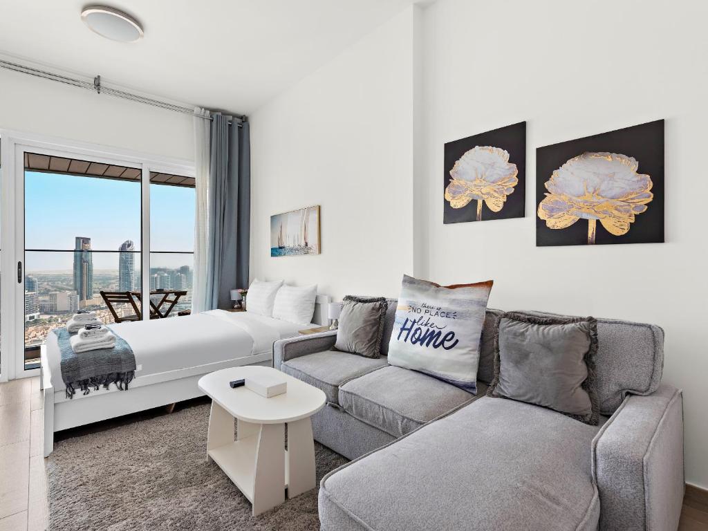 ein Wohnzimmer mit einem Sofa, einem Bett und einem Fenster in der Unterkunft Spacious Studio With A Sofa Bed In JVC in Dubai