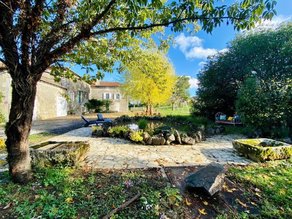 un jardín con un árbol y un camino de piedra en Superbe manoir du XVIIe siècle surplombant le fleuve de la Charente, en Alloué