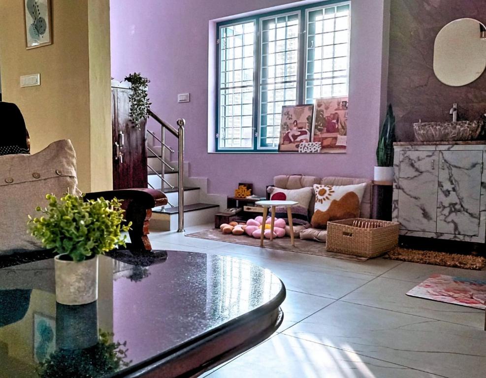 un soggiorno con pareti viola e tavolo in vetro di Guestland Homestay a Cochin
