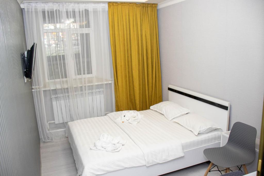 1 dormitorio con cama blanca y ventana en AG Hotel, en Almaty