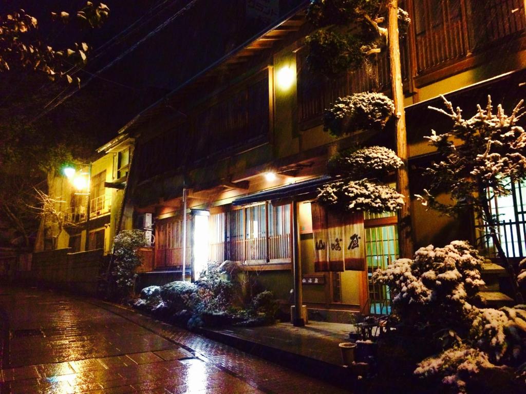 um edifício numa rua à noite com luzes em Yudanaka Onsen Yamazakiya em Yamanouchi