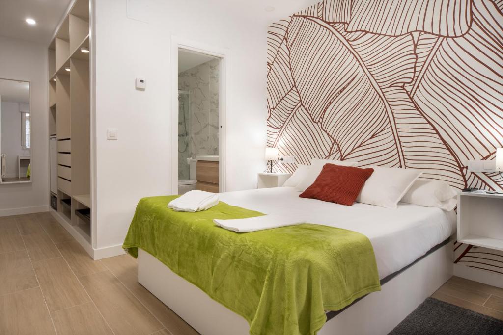 um quarto com uma grande cama branca e um cobertor verde em Vizcainos Garden em Segóvia