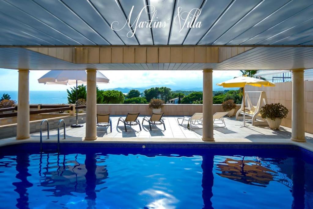 - une piscine avec des chaises et un parasol dans l'établissement Martin 's Villa. House on the beach with pool, à Lloret de Mar