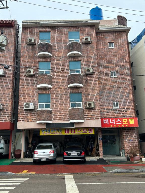 dois carros estacionados em frente a um edifício de tijolos em Venus Motel em Mokpo