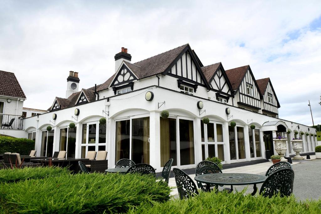 ein Gebäude mit einem Tisch und Stühlen davor in der Unterkunft Buckatree Hall Hotel in Telford