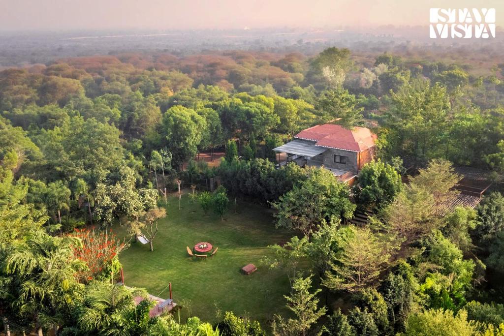 an aerial view of a house in the middle of a forest at StayVista's Apple Farms - Urban Oasis with Outdoor Pool & Expansive Lawn in Sohna