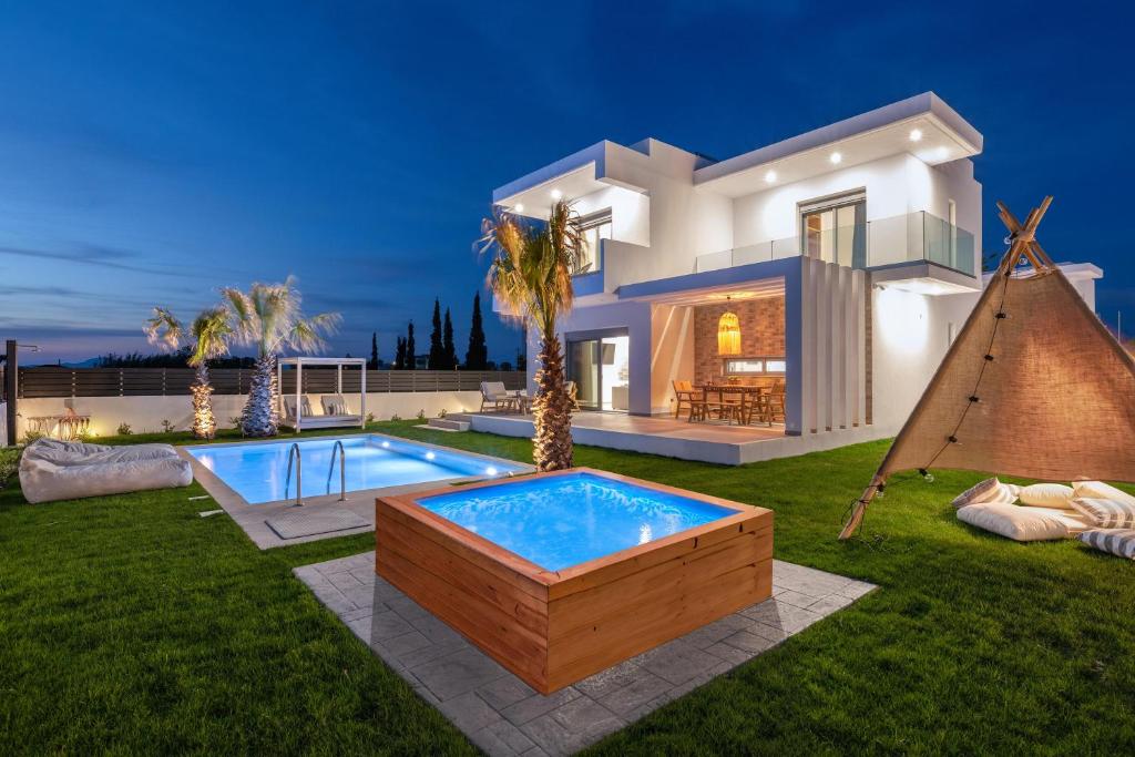 a villa with a swimming pool in front of a house at Martinis Villas in Kremasti