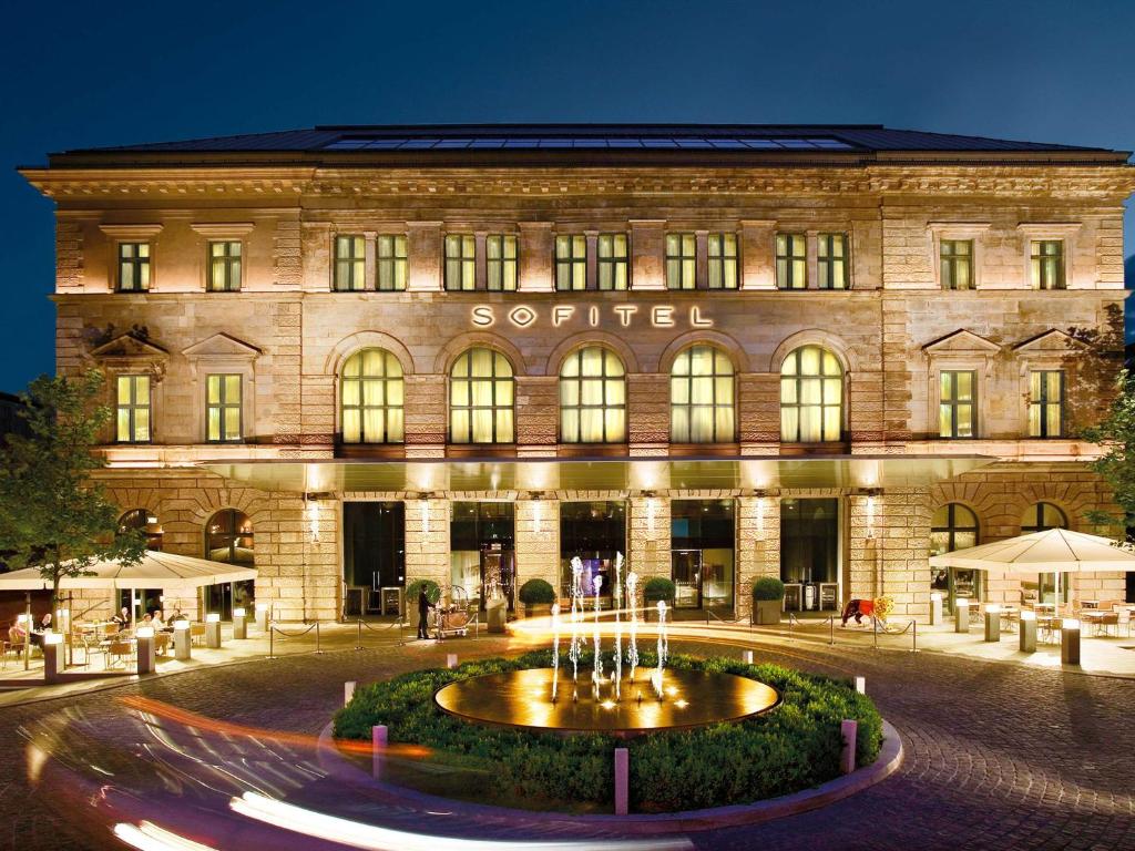 un edificio con una fontana di fronte di Sofitel Munich Bayerpost a Monaco