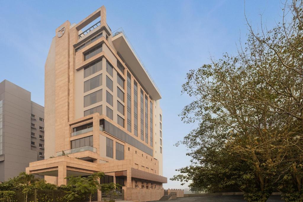 a tall building with a tree in front of it at Fortune Park, East Delhi - Member ITC Hotels' Group in New Delhi