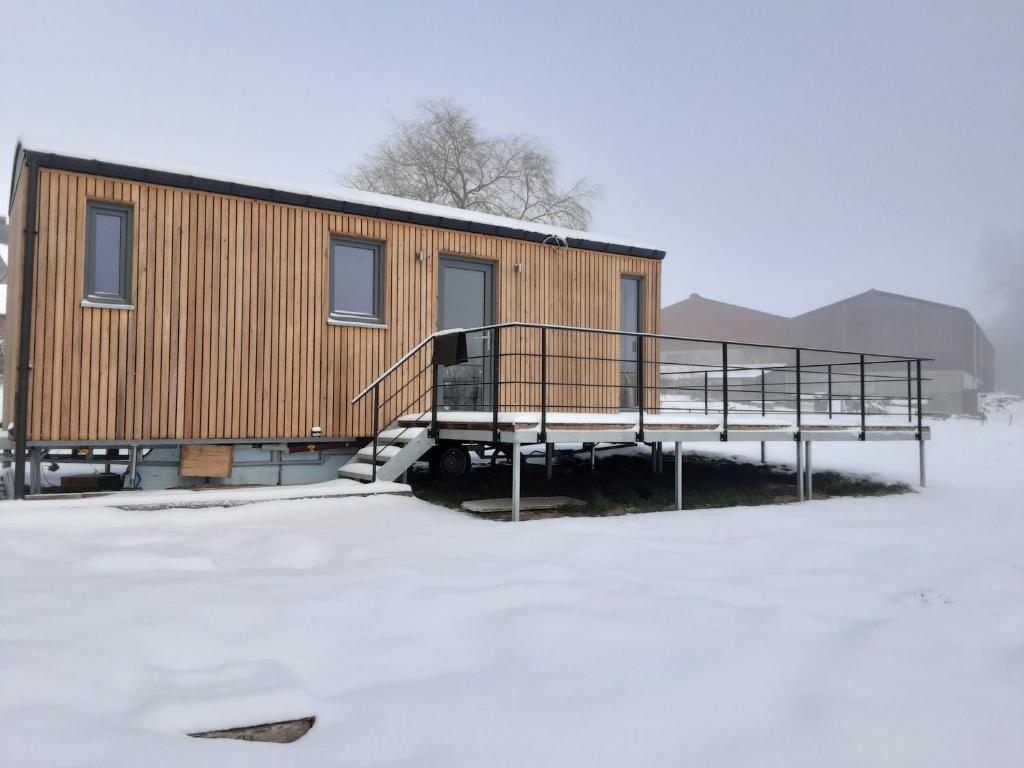 a house with a deck in the snow at Au p'tit pré des salers in Hamois