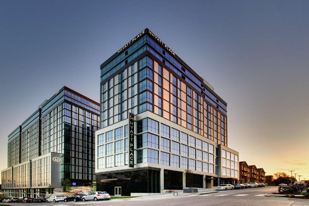 Un edificio alto con ventanas de vidrio en una calle de la ciudad. en Hyatt Place Iowa City Downtown, en Iowa City