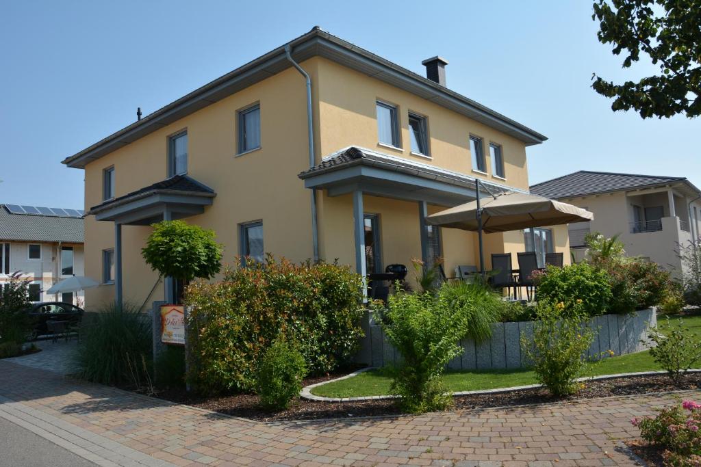 a large yellow house with bushes in front of it at Gästehaus Dolce Vita in Rust