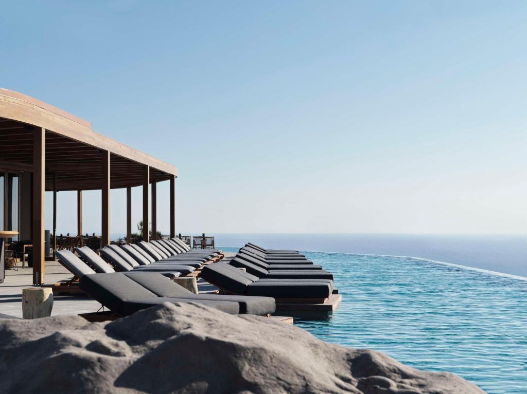 a row of chaise lounges on a pier near the ocean at Magma Resort Santorini, In The Unbound Collection By Hyatt in Vourvoulos