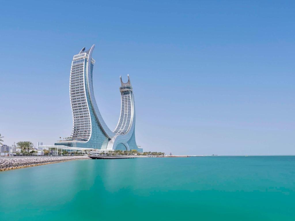 un edificio alto junto a un cuerpo de agua en Fairmont Doha, en Doha