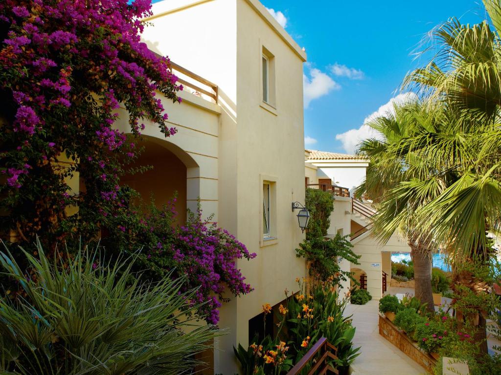 a house with purple flowers on the side of it at Grecotel Marine Palace & Aqua Park in Panormos Rethymno