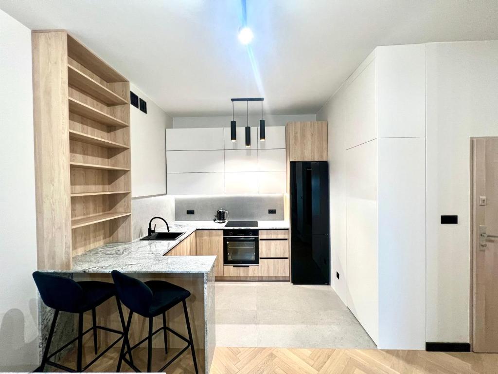 uma cozinha com armários brancos e um frigorífico preto em Apartament Zdrojowy Zakątek em Busko-Zdrój