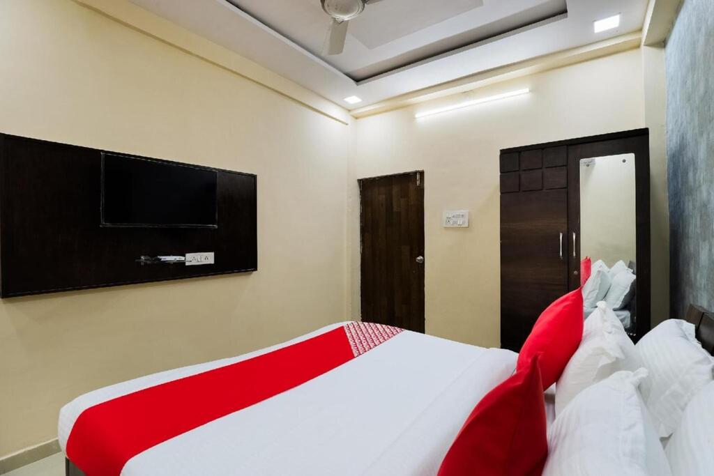 a bedroom with a red and white bed and a flat screen tv at Hotel Sunrise in Naroda