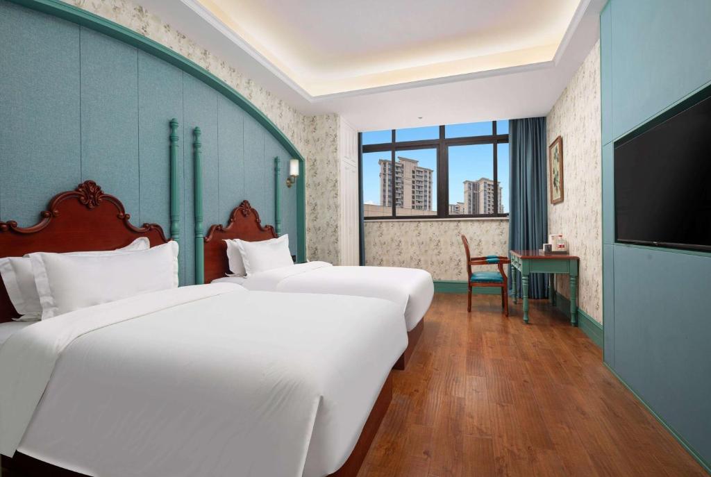 a hotel room with two beds and a flat screen tv at Days Inn by Wyndham Chongqing Tongliang in T'ung-liang-hsien